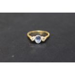 A HALLMARKED 18 CARAT GOLD SAPPHIRE AND DIAMOND RING, set with central light blue sapphire and two