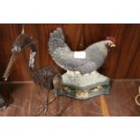 A CAST IRON HEN AND CHICKS DOOR STOP TOGETHER WITH A MODEL OF A HERON