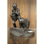 A BRONZE EFFECT MODEL OF MAN FEEDING A PIG