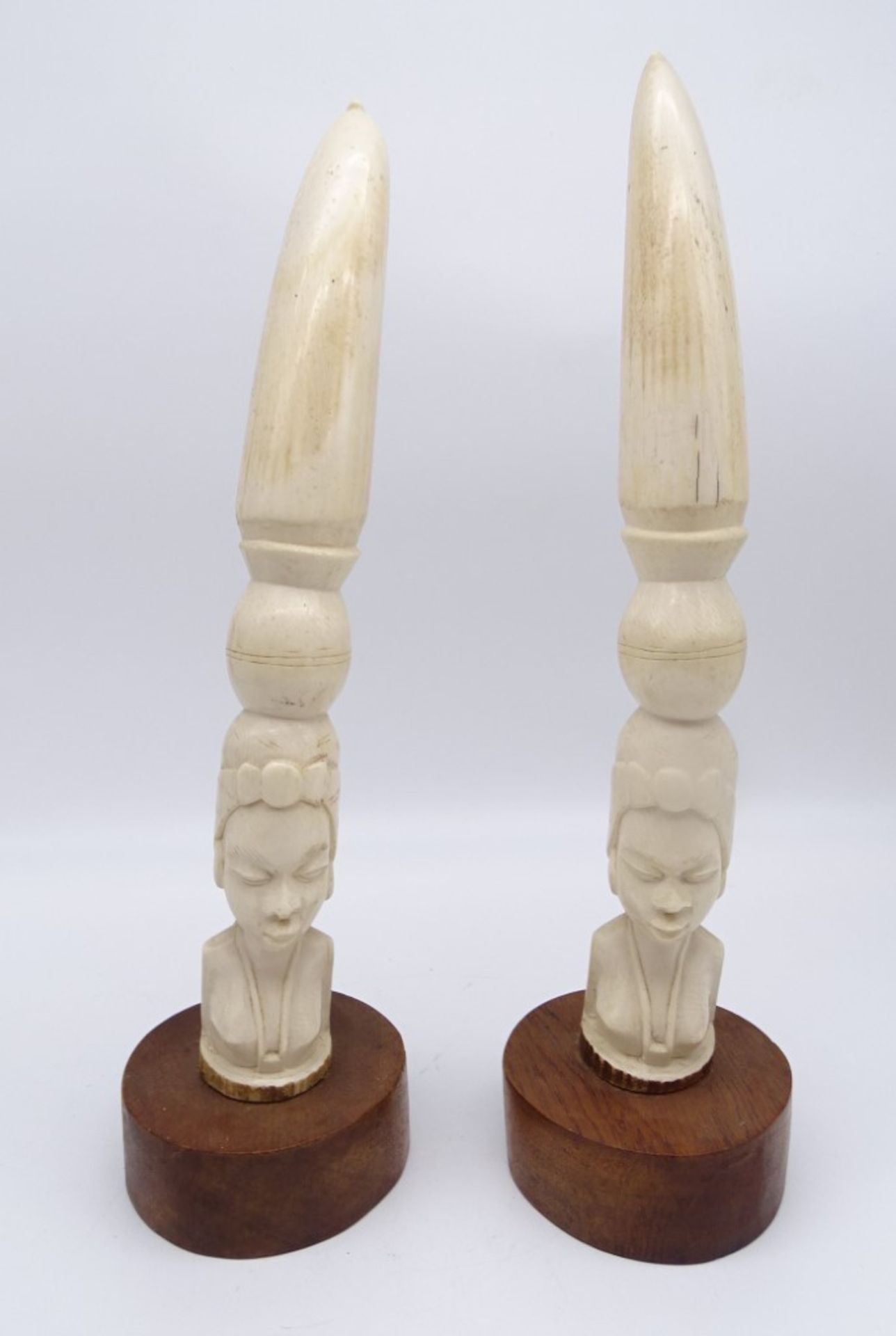 2 alte afrikanische Beinschnitzereien auf Holzsockel, "Die Wasserträgerin", H. 40 und 41 cm, mit le