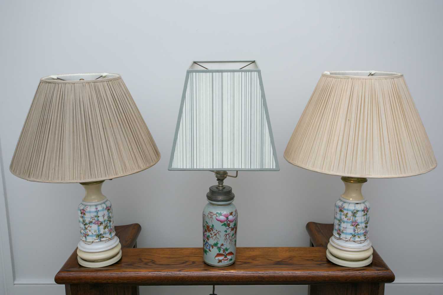 A pair of French faux oil porcelain table lamps, fitted for electricity with rise and fall pleated