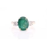 A large emerald and diamond three stone ring set in 18ct yellow gold, the central oval mixed-cut