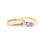 A three-stone diamond ring and a wedding band. The three-stone diamond ring is claw set with three