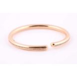 A rose coloured and diamond set torque style bangle; the tubular hollow bracelet set to the centre