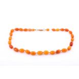 An amber bead necklace consisting of thirty-one graduating beads from 18mm to 8.5mm in length with a