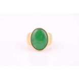 A yellow metal signet style ring set with an oval jade cabochon measuring 20mm x 15mm, the