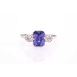 A tanzanite and diamond three stone ring, the emerald-cut tanzanite measuring 7.5 x 5.5mm with a