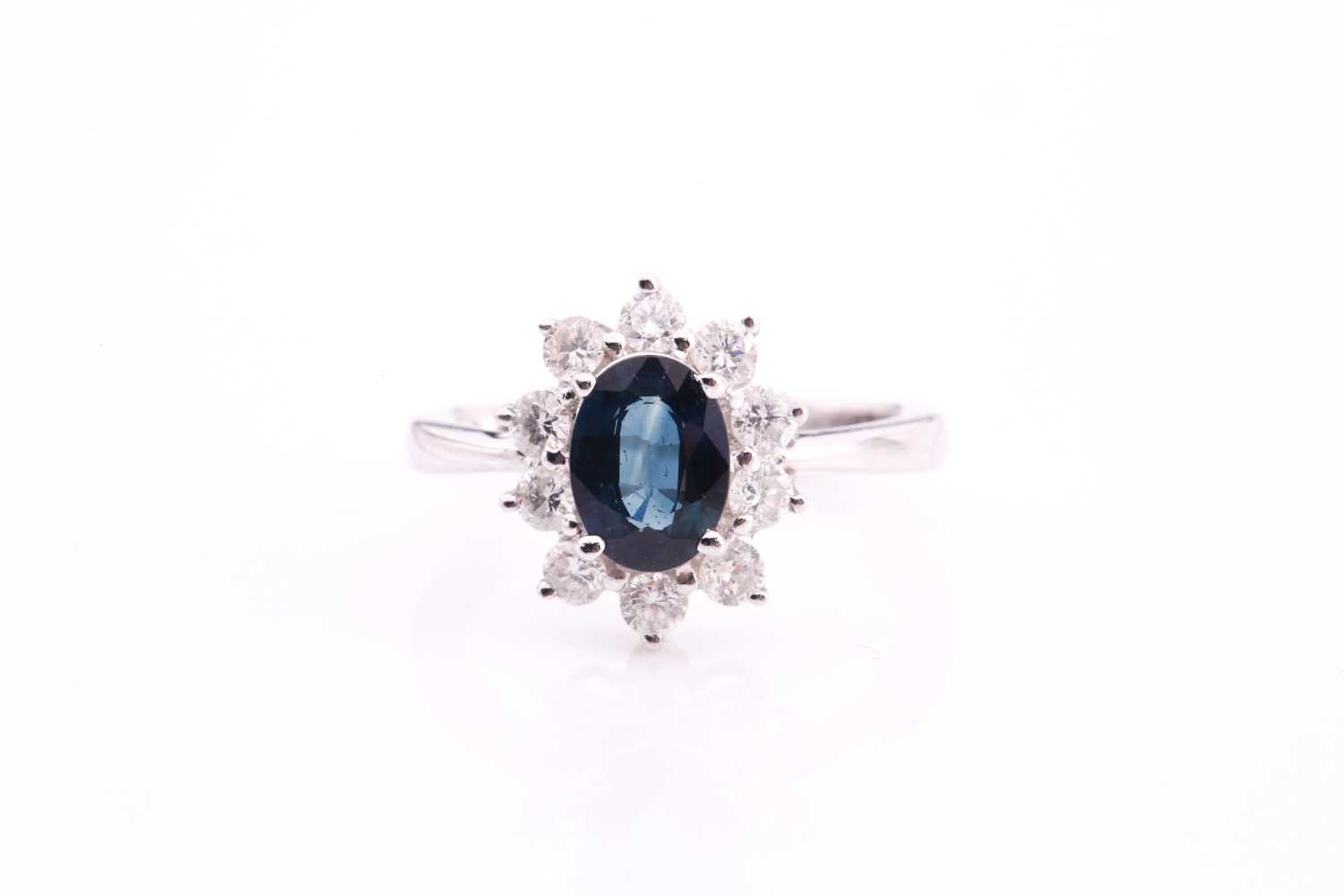 A sapphire and diamond cluster ring, set with an oval sapphire measuring 7.1mm x 5.6mm with a weight