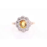 A yellow sapphire and diamond cluster ring, set with an oval yellow sapphire weighing 1.20ct