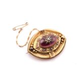 A Victorian garnet and pearl mourning brooch; the elliptical-shaped panel centrally set with an oval