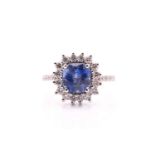 A sapphire and diamond cluster ring, the rectangular mixed cut violet-blue sapphire, within a