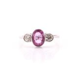 A pink sapphire and diamond three stone ring the white metal mounted oval mixed cut pink sapphire