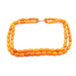 An amber two strand bead necklace; the slightly graduated oval beads of butterscotch colour. 54cm