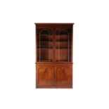 A Victorian mahogany two-door library bookcase, the doors with arched glazed panels decorated with