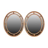 A pair of George III Adam style gilt framed oval mirrors, 20th century, with moulded paterae between