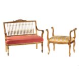 An Edwardian giltwood two-seat open arm settee, with carved cresting, turned spindle back and