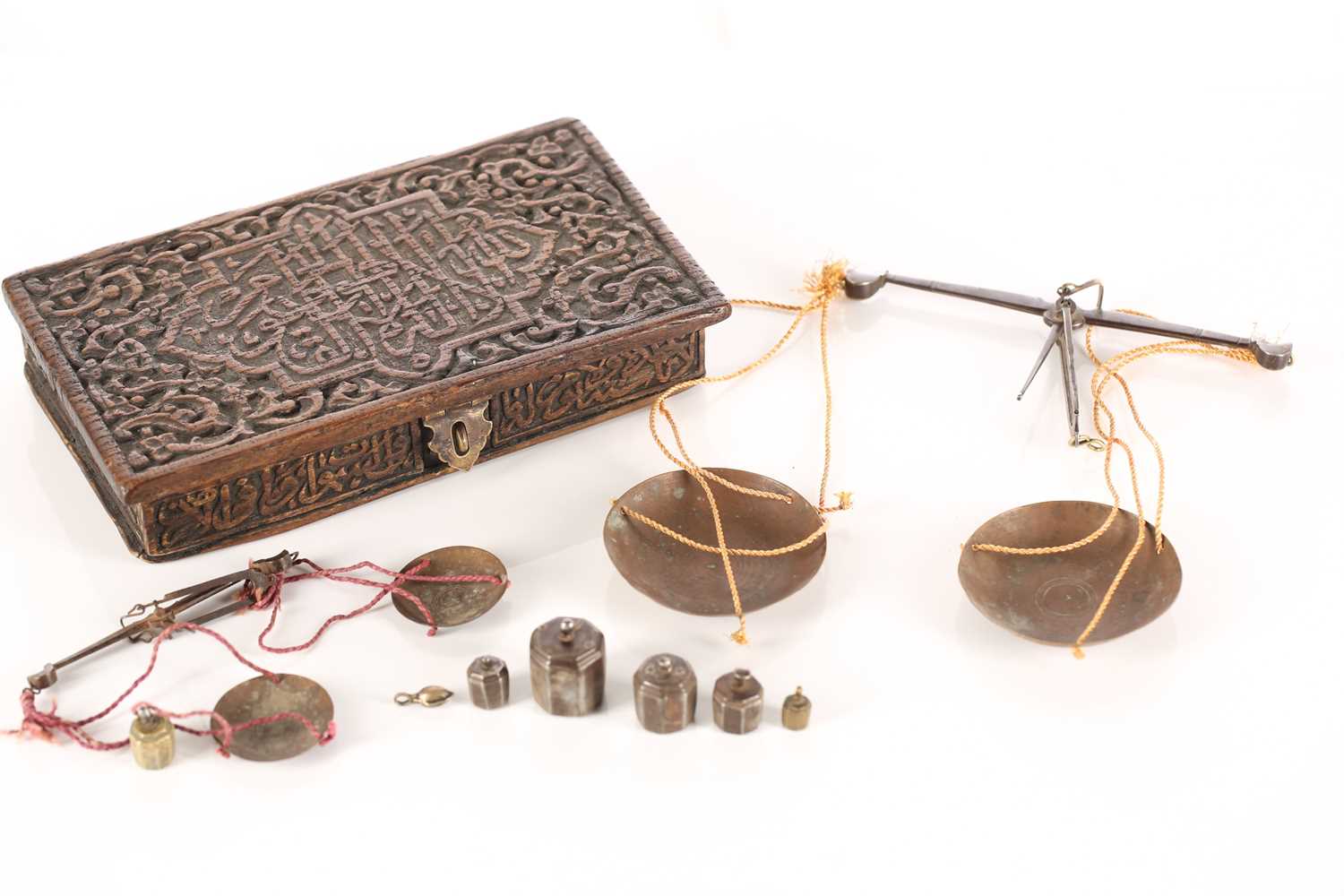 An Eastern coin scale in a fitted teak case carved with Islamic script, with two beams and pans in