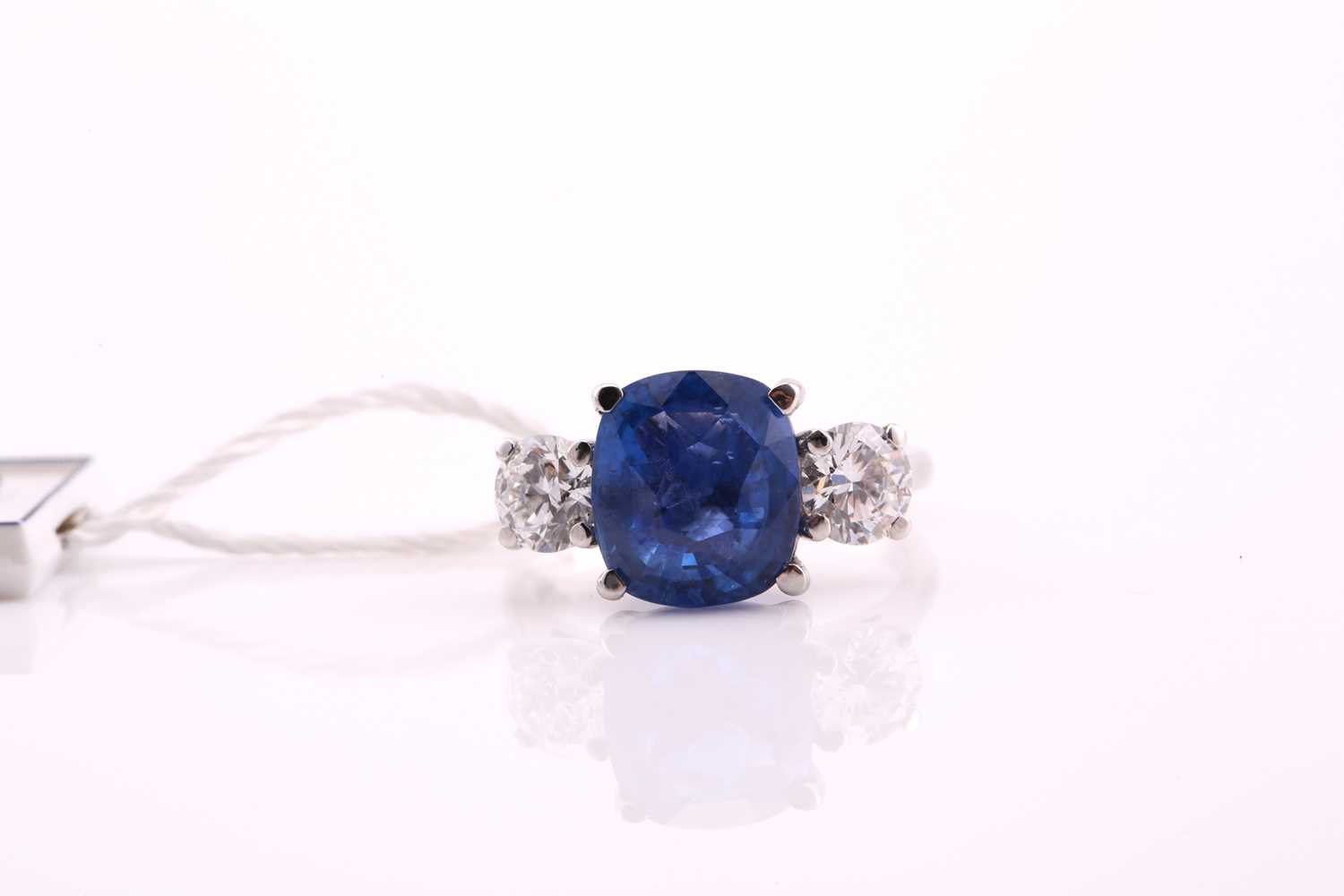 A sapphire and diamond three stone ring, the cushion mixed cut sapphire 4.21 carats, flanked two