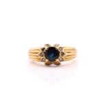 A yellow metal stamped 750 sapphire and diamond ring, consisting of a central round sapphire
