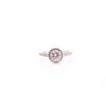 A diamond cluster ring; the brilliant cut diamond in four claw mount, above a hallo border of
