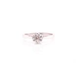 A single stone diamond ring; the round brilliant cut diamonds n six claw mount to a plain 18 carat