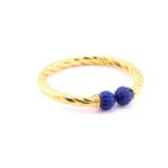 A torc style hinged bracelet, the yellow ropetwist mount terminating in two ‘melon’ carved lapis