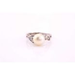 A cultured pearl and diamond ring, mid 20th century, the 8.7mm light cream pearl, with three
