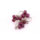 A ruby spray brooch set with eleven oval cabochon rubies set in white base metal, 4.6cm