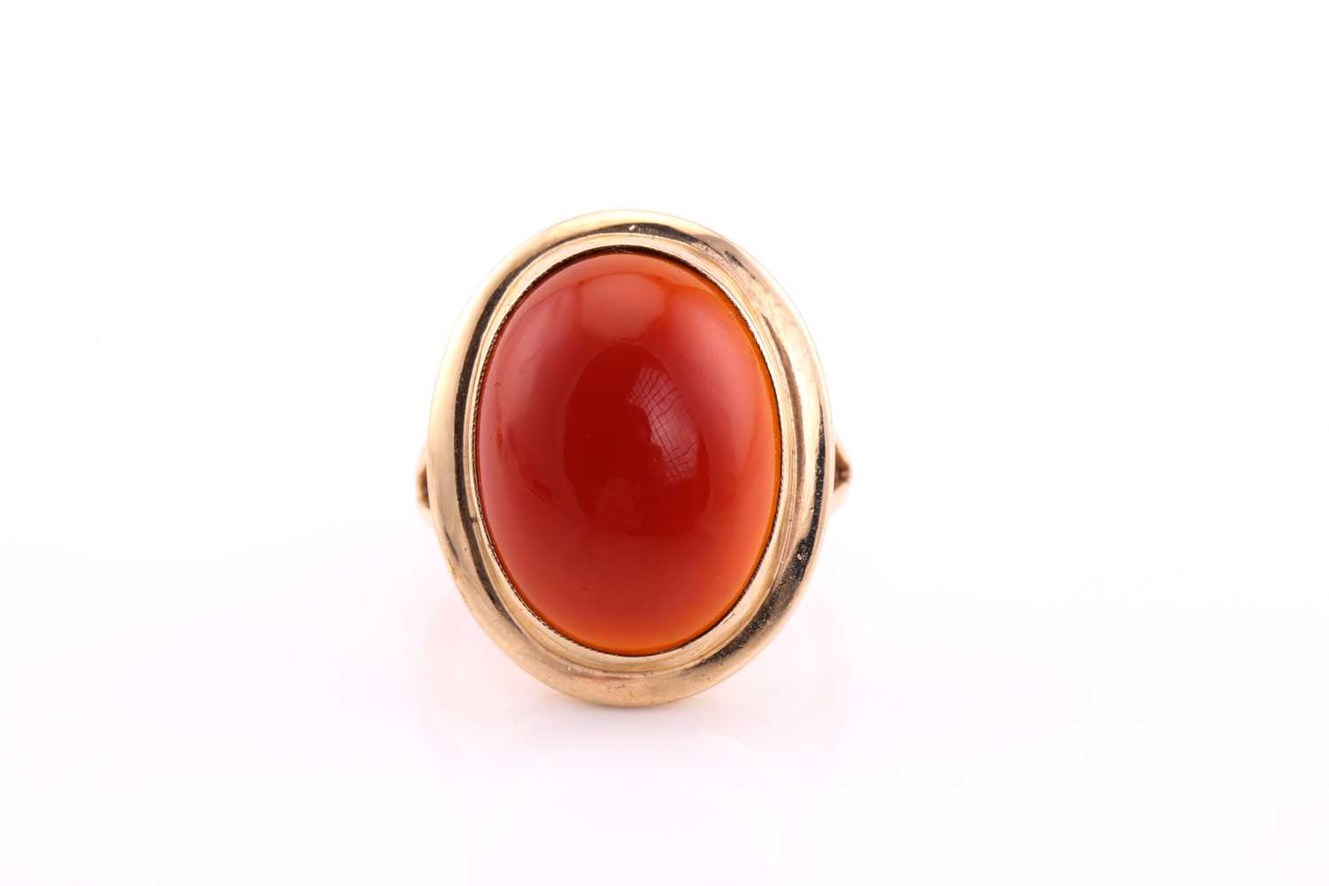 A carnelian cabochon ring, mid 20th century, the 19 x 14.5mm oval cabochon collet set to a yellow