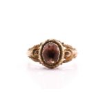 An early 19th century gold and pink topaz mourning ring; the foiled, oval cut stone in cut down