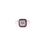 A diamond and sapphire cluster ring; the round brilliant cut diamond in four claw mount within a