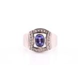 A tanzanite and diamond ring on white metal stamped 750, consisting of a central oval tanzanite of