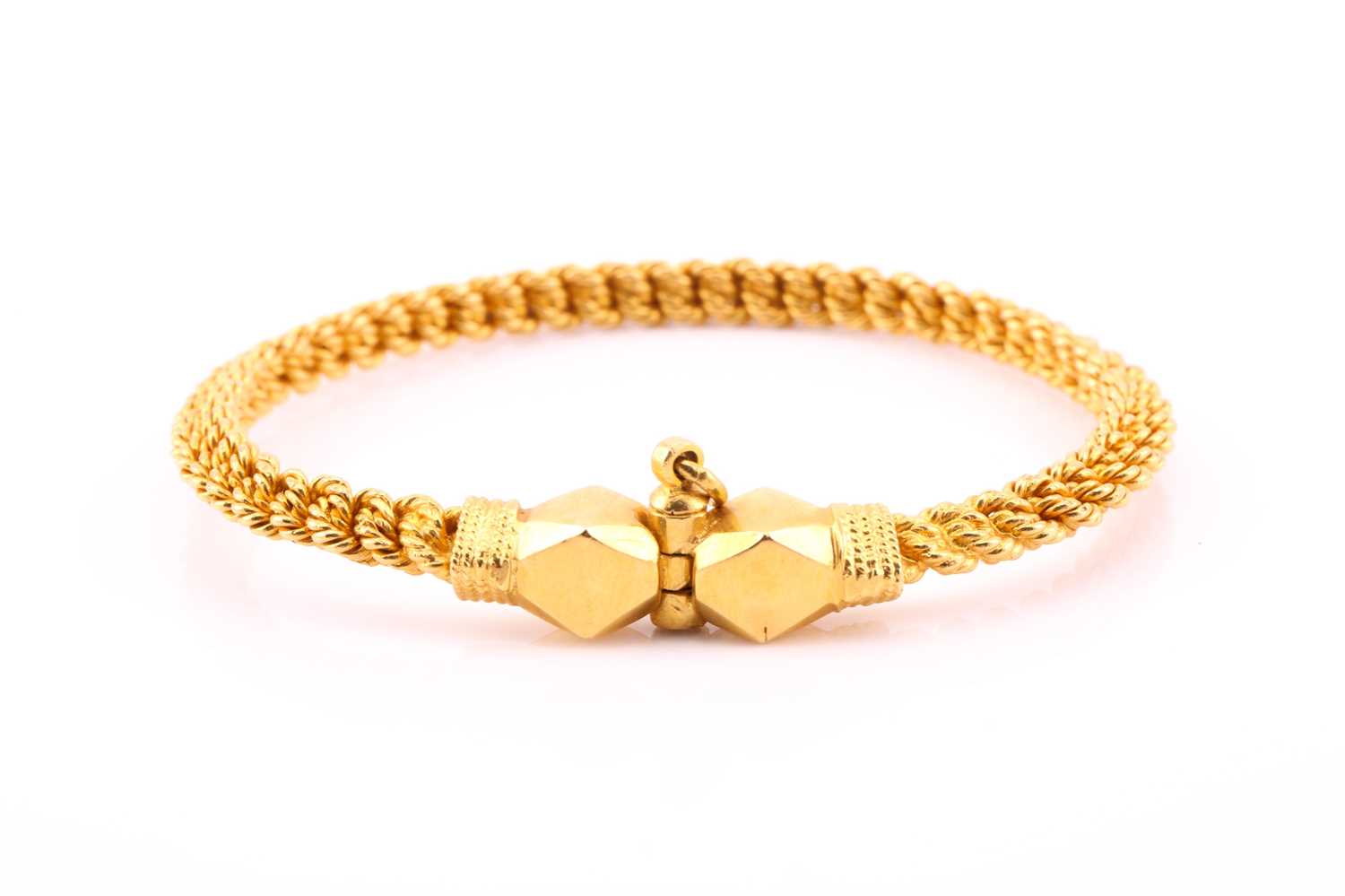 A yellow metal torque style bangle, the rope twist bangle with faceted terminals and screw-down