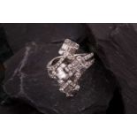 A diamond dress ring Of bifurcated design, obliquely-set to the front with four clusters of baguette