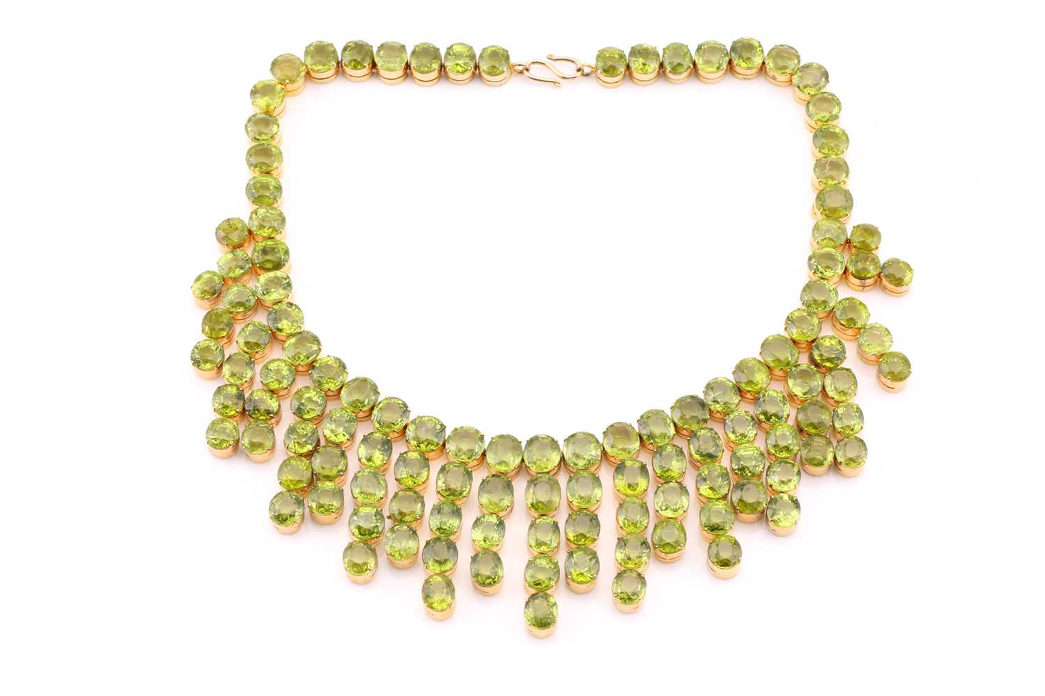 A peridot fringe necklace, oval and round cuts claw set to gilt metal mount, peridots averaging 8.