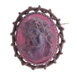 A moulded glass cameo style brooch; the purple frosted glass bust portrait of a woman with ringlets