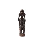A Baule maternity figure, Ivory Coast, the seated figure with sculpted coiffure linear carved with