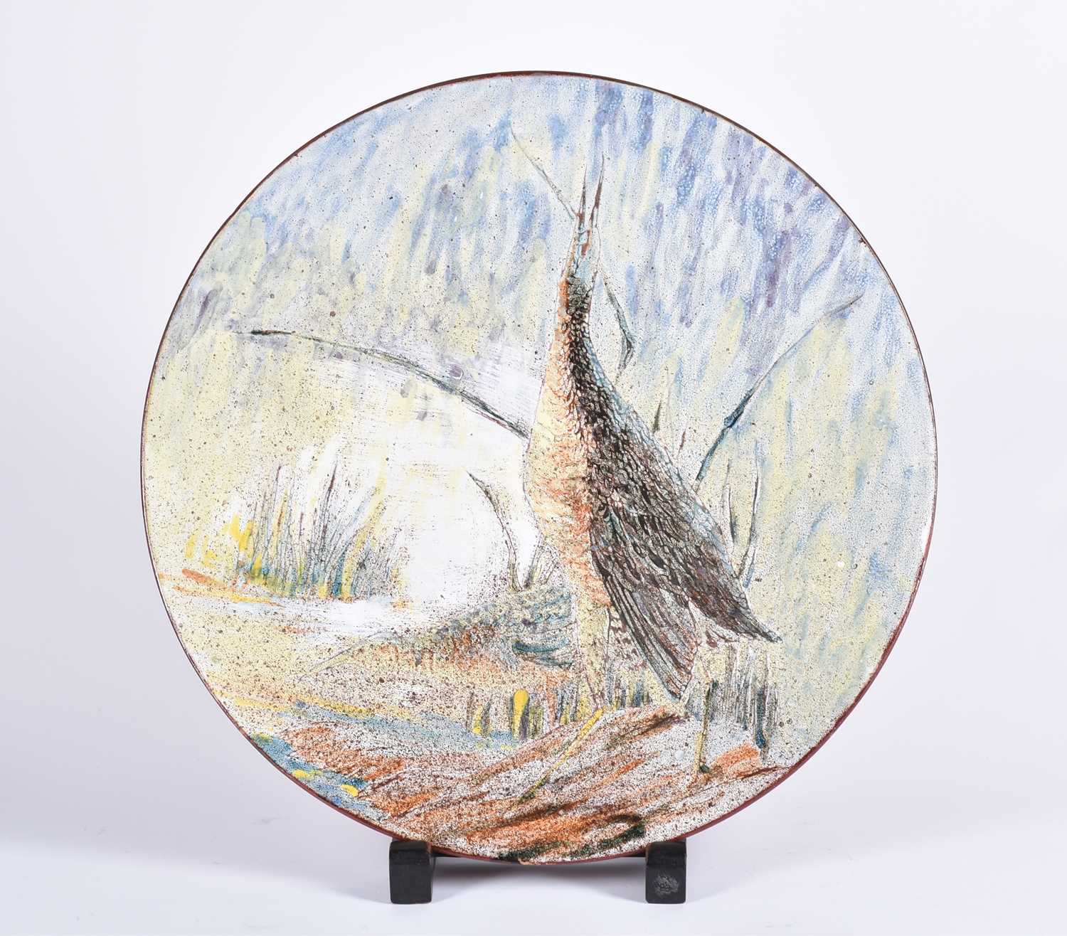 A large Chelsea Pottery terracotta charger, painted with a wading bird by reeds and a stream,