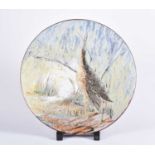 A large Chelsea Pottery terracotta charger, painted with a wading bird by reeds and a stream,