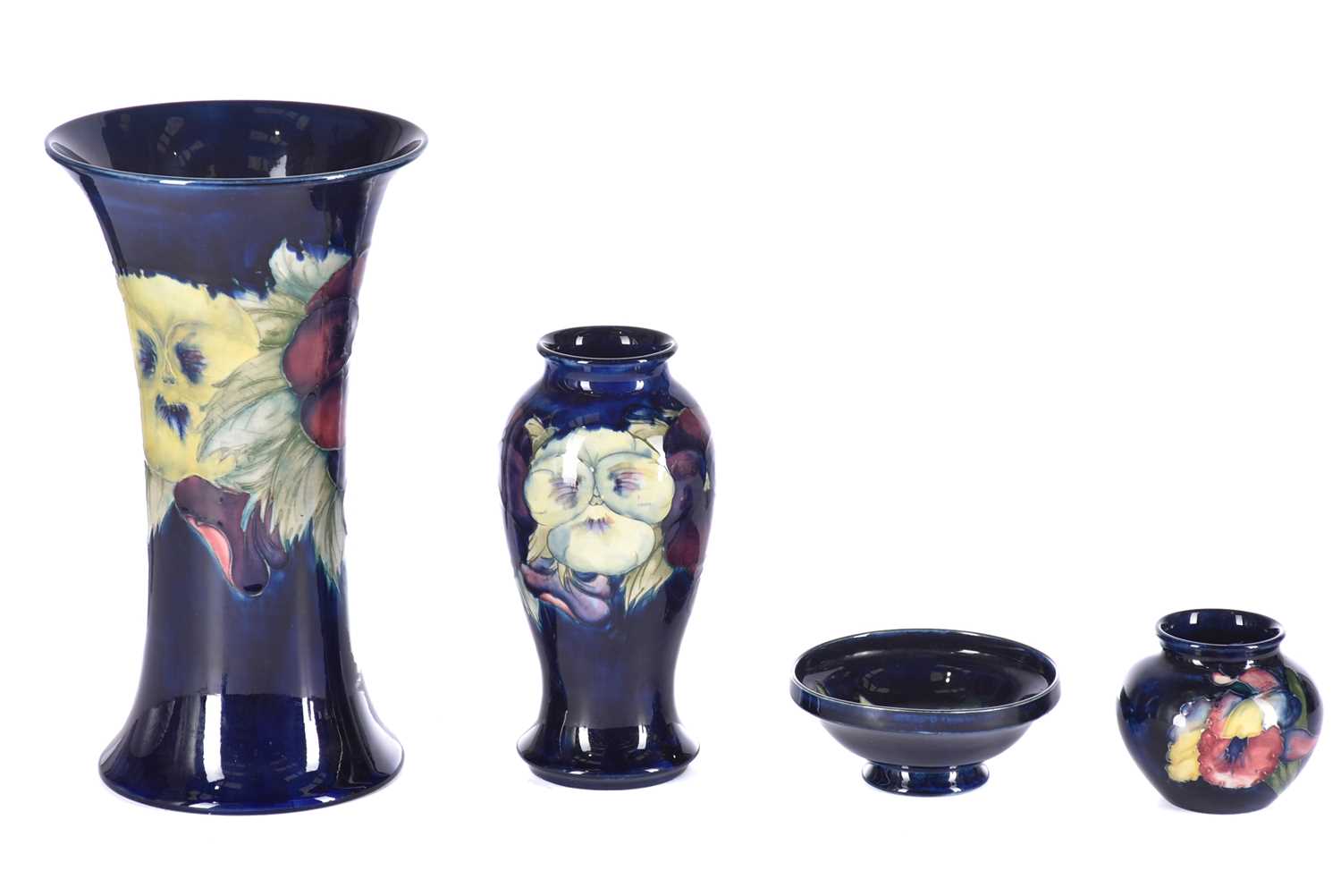 Four items of Moorcroft, comprising a large pansy vase, another smaller pansy vase, a small pedestal