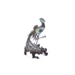 A small unmarked silver and cloisonne enameled peacock ornament on a wooden stand, probably Indian