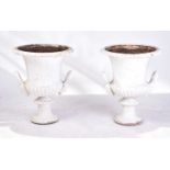 A pair of cast iron two-handled campana urns with gadrooned rims. on fluted circular spreading