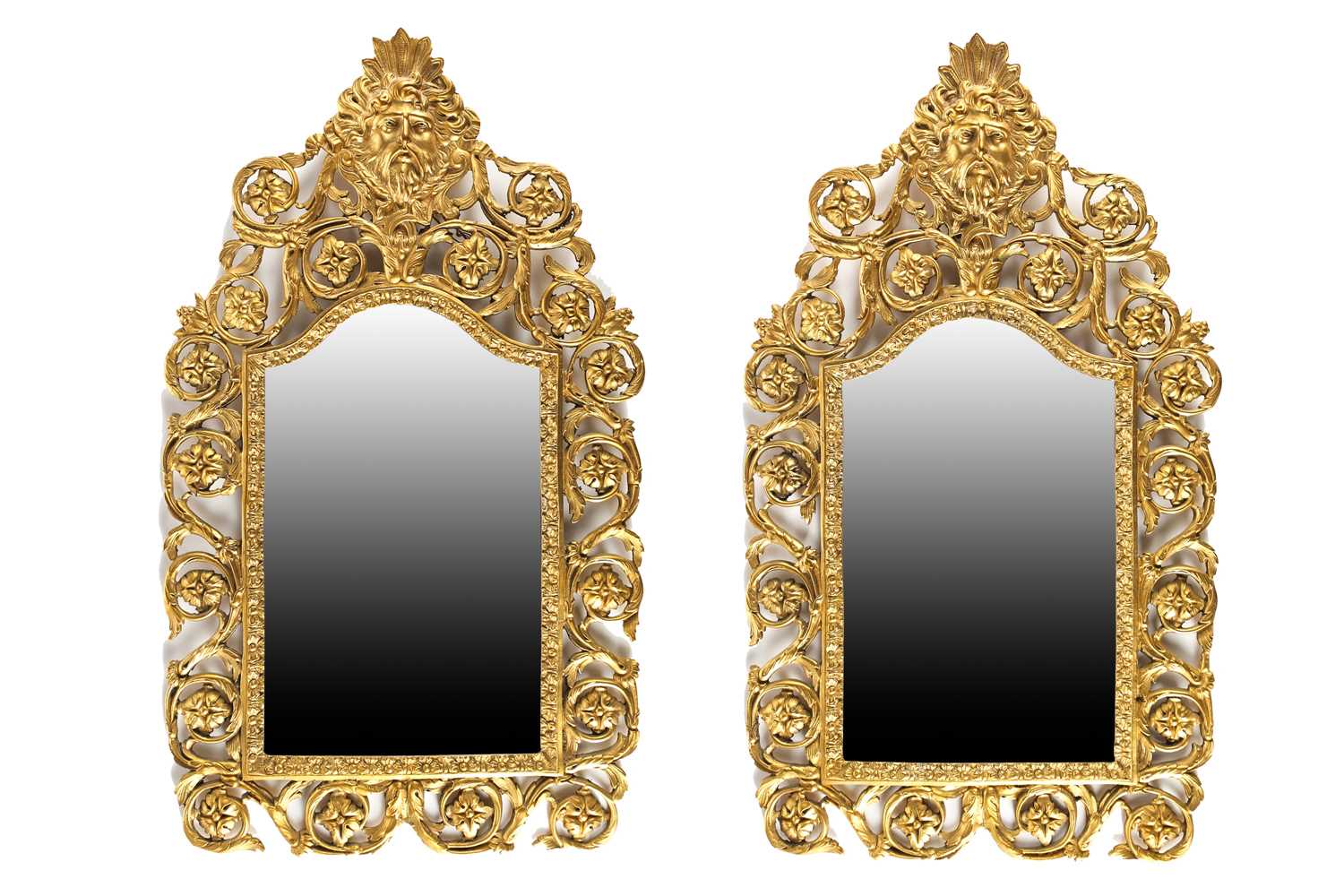 A pair of Victorian gilt brass arched wall mirrors, each cast with the mask of Zuess to their