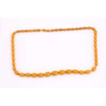 A butterscotch coloured amber bead necklace, strung with barrel-shaped opaque beads, approximately