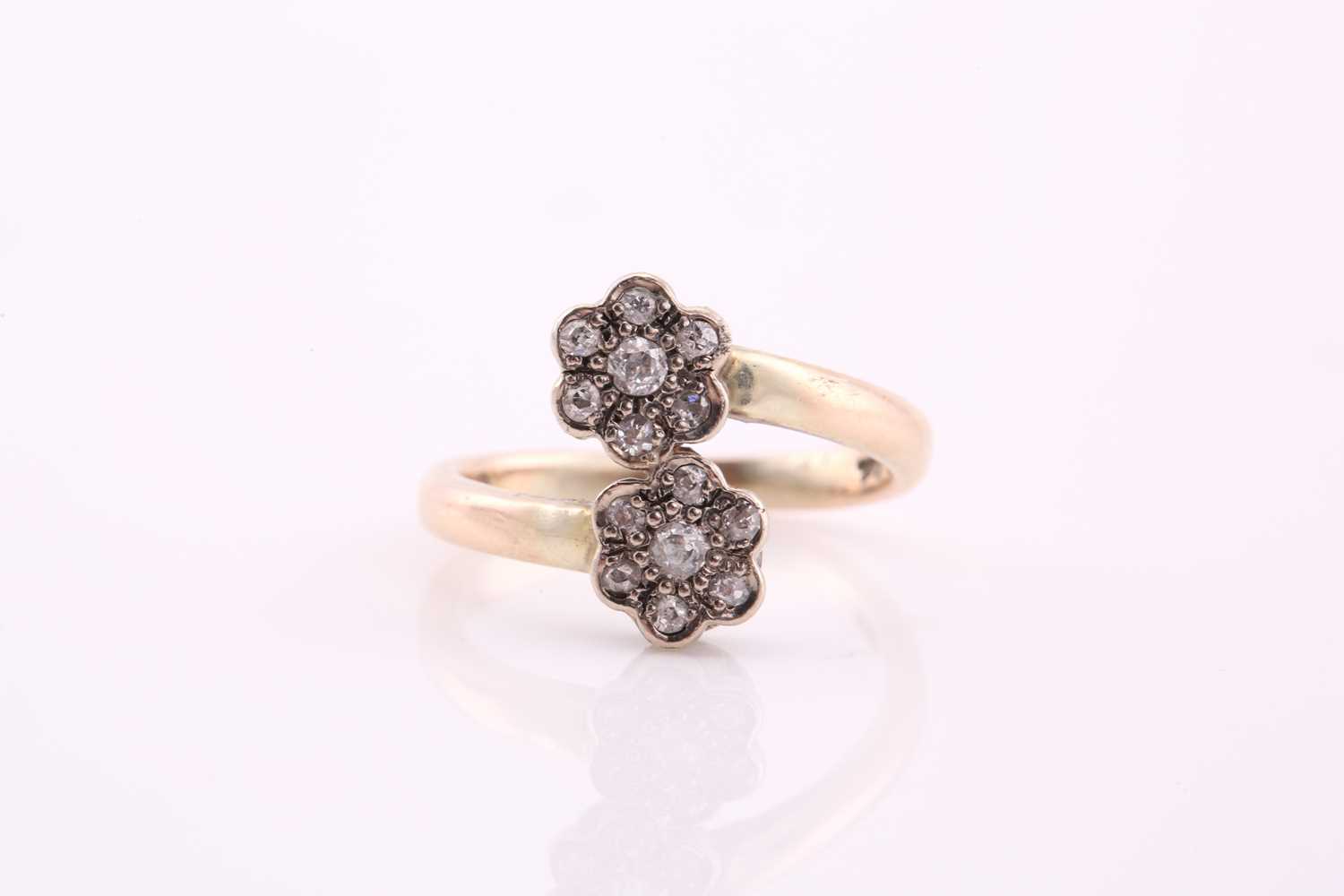 A bypass diamond ring with double daisy heads, consists of diamond clusters estimating a total