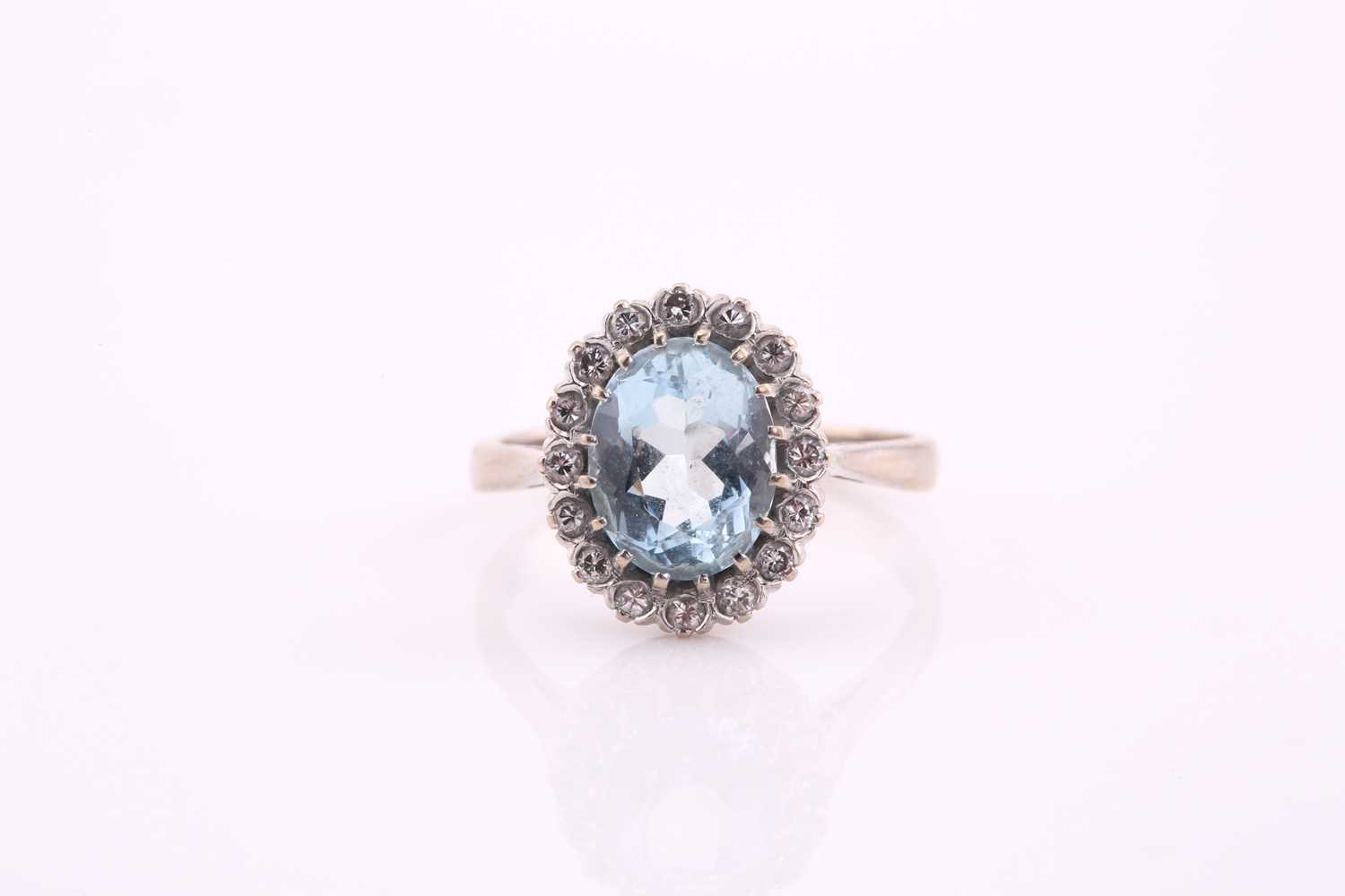 An aquamarine and diamond cluster ring, the oval mixed cut aquamarine 10.2mm x 8mm, surrounded by