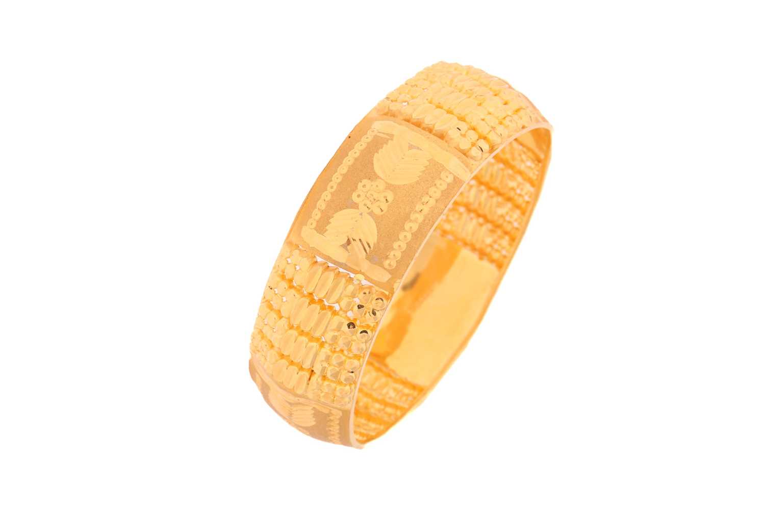 A yellow metal bangle, decorated with pierced, engraved and burred patterns, as well as sandblast