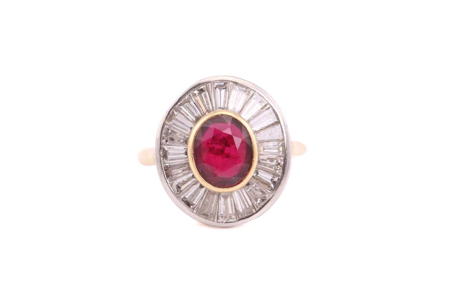 A ruby and diamond cluster ring; the central oval cut ruby in rub over mount within a surround of