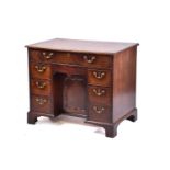 A George III mahogany kneehole writing desk the frieze drawer with fitted interior and baize lined