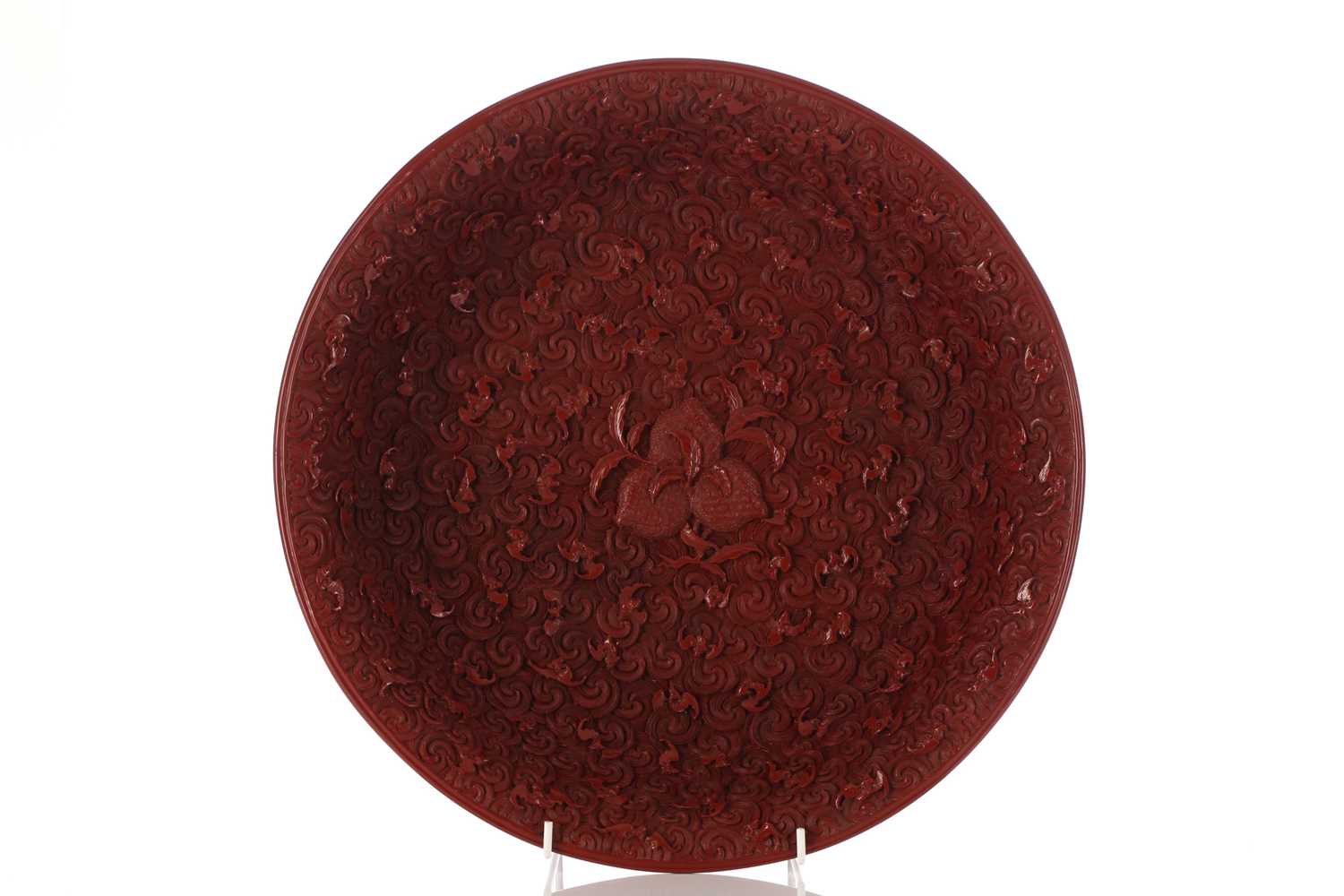 A Chinese cinnabar lacquer dished bowl, 20th century, decorated with three peaches to the centre